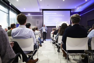 Spreker geeft een presentatie voor een groep bezoekers tijdens een sessie van Esri Connect.